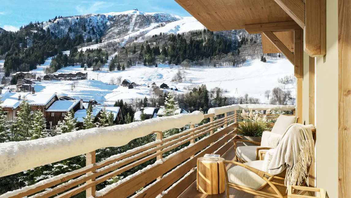 Cette image présente une vue spectaculaire depuis le balcon d'un chalet contemporain situé dans une station de ski alpine. Au premier plan, un balcon en bois clair avec garde-corps à claire-voie accueille un fauteuil confortable habillé d'un plaid beige, invitant à la détente. La structure apparente en bois massif du chalet crée une ambiance chaleureuse et authentique. L'arrière-plan révèle un paysage de montagne hivernal exceptionnel : des pistes de ski serpentent sur les versants enneigés, parsemés de forêts de conifères. Le village traditionnel s'étend dans la vallée avec ses chalets caractéristiques à toits pentus. Au loin, les sommets majestueux dominent le panorama sous un ciel bleu azur ponctué de nuages blancs. L'ensemble illustre parfaitement l'art de vivre alpin : confort moderne, architecture traditionnelle et connexion privilégiée avec la nature montagnarde. Cette vue incarne l'attrait des résidences d'altitude offrant à la fois proximité avec les pistes et qualité de vie exceptionnelle.