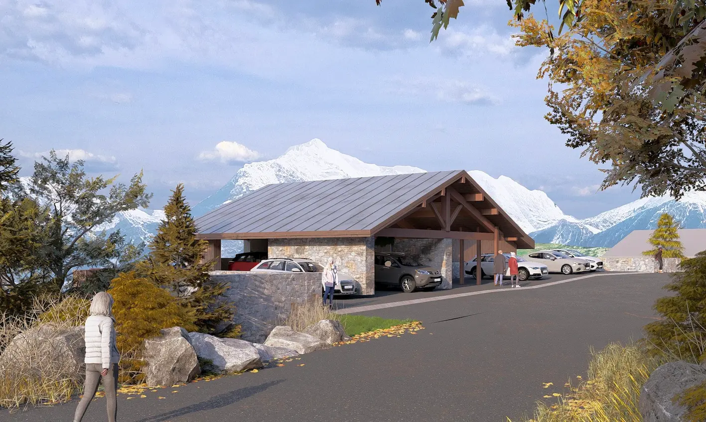 Cette perspective architecturale présente un bâtiment de stationnement conçu pour s'intégrer harmonieusement dans le paysage montagnard. La construction adopte les codes de l'architecture alpine avec un large toit à double pente couvert de bac acier anthracite, une charpente apparente en bois massif et des murs en pierre locale. Le parking semi-ouvert offre plusieurs emplacements couverts visibles au premier plan, avec une structure mêlant boxes fermés en maçonnerie de pierre et espaces abrités sous l'avancée de toiture soutenue par des poteaux bois. Cette conception permet de protéger les véhicules des intempéries tout en maintenant une ventilation naturelle. L'aménagement paysager privilégie une intégration naturelle avec des rochers affleurants, des graminées automnales dorées et des conifères encadrant la construction. Le site bénéficie d'une exposition exceptionnelle face à un amphithéâtre de montagnes majestueuses dont les sommets enneigés se détachent sous un ciel nuageux. Plusieurs personnages animent la scène, soulignant la dimension humaine et fonctionnelle de l'équipement. L'arrière-plan révèle un parking extérieur complémentaire et la vallée alpine s'étendant vers les massifs lointains.